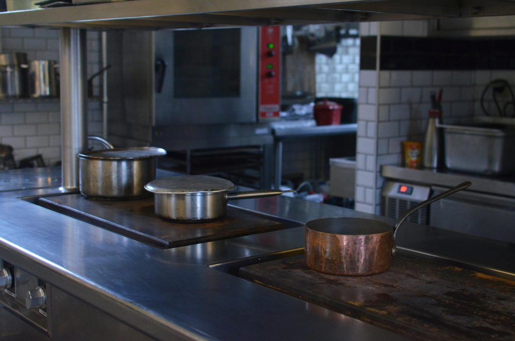 Stainless steel pots on a kitchen counter in a professional restaurant setting.